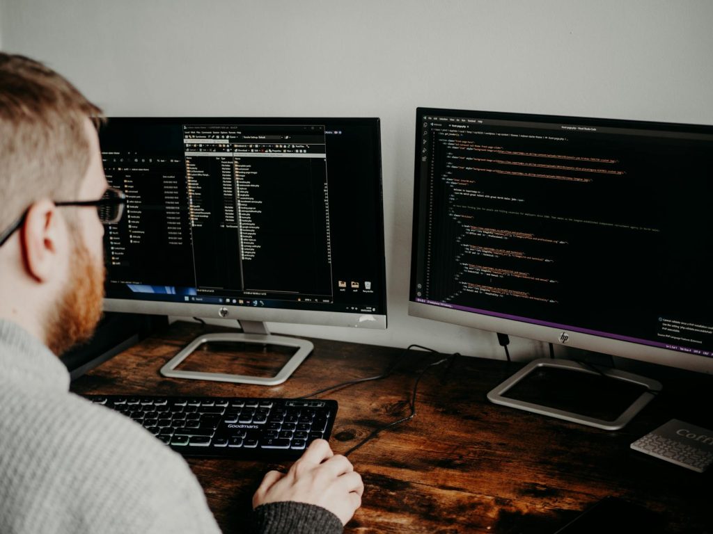 man coding on computers sitting at desk